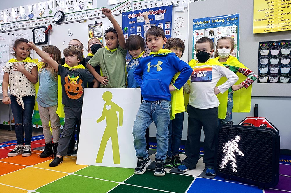 school children wearing capes and posing with a poster of mr walker