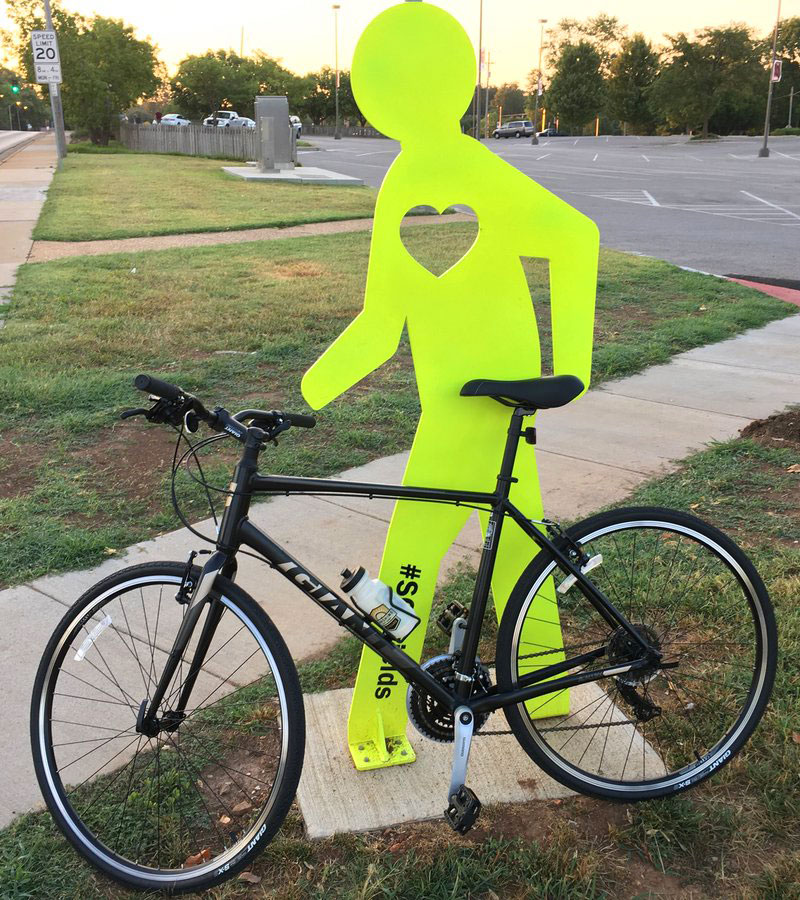 yellow 'mister walker' metal sculpture with bicycle